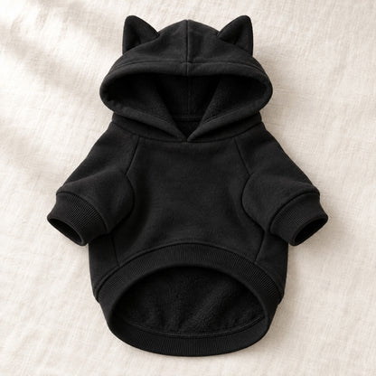 Varmende hettegenser for hund i sort fleece, uten trykk, lagt flatt på lin