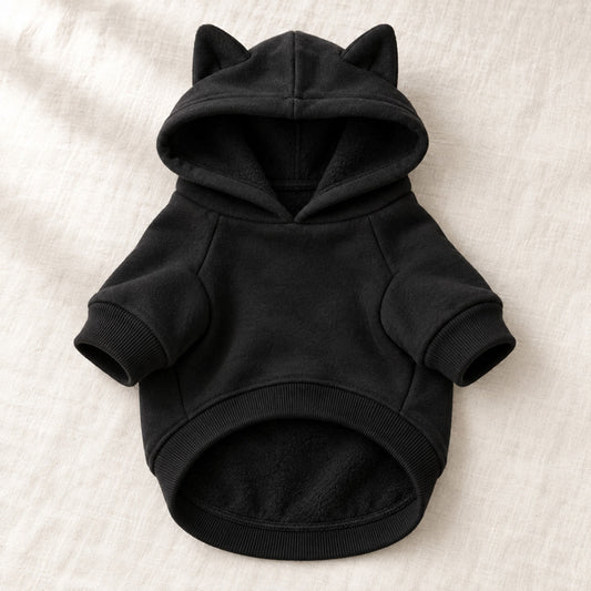 Varmende hettegenser for hund i sort fleece, uten trykk, lagt flatt på lin
